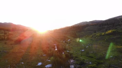 Aerial ascending shot with sun rays hitting the lens in the Grand Teton National Park.