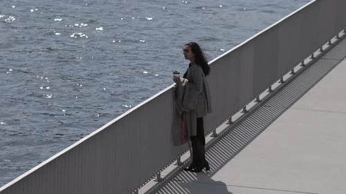 The Crisp Morning Air Complements Her Brisk Walk Along the River a Coffee Cup a Constant Companion