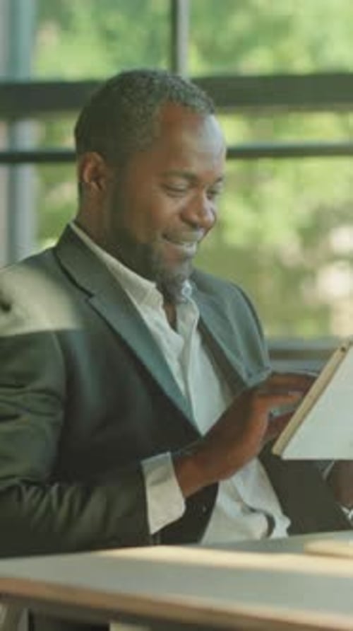 Man in Suit Uses Tablet at Desk Indoors