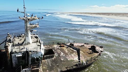 Aerial drone view of an abandoned shipwreck on the remote Skeleton Coast of Namibia with ocean waves
