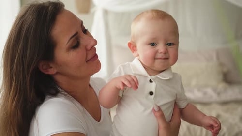 Loving Mother Holding Smiling Baby Indoors