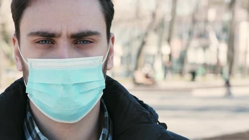 Man in Medical Protective Mask Standing in City Park