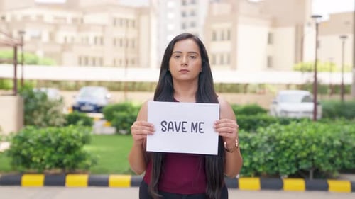 Woman Holding Save Me Sign in City Area