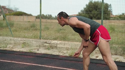 Athletic Man Sprinting on Running Track Outdoors