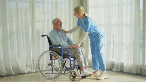 Elderly Man in Wheelchair with Nurse Support