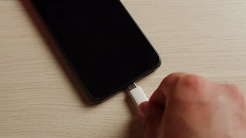 Carga de un smartphone con cable USB en una mesa de madera
