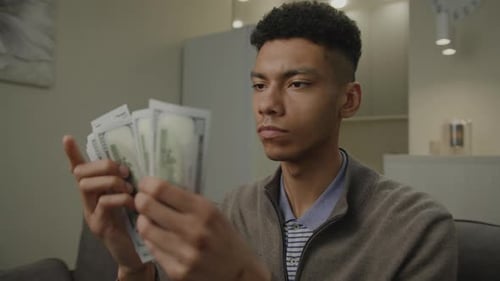 Black Man Counts Money US Dollars Millennial African American Man Holding Currency Sitting at Home