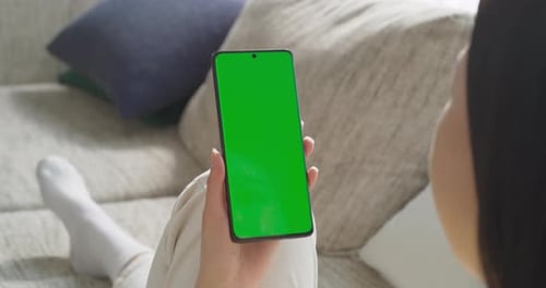 Anonymous Young Female Using a Smartphone with Green Screen Mock Up Display. Browsing Internet, Ch