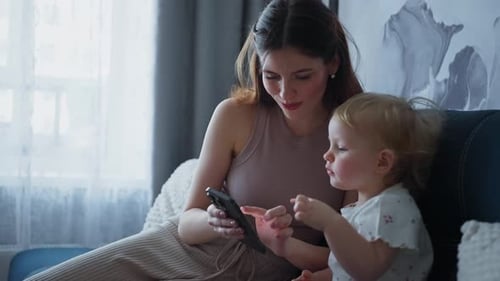 Mother and Child Looking at Smartphone Together Indoors