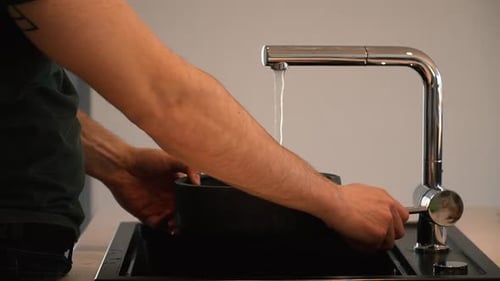 Person Filling A Bowl With Tap Water In The Kitchen