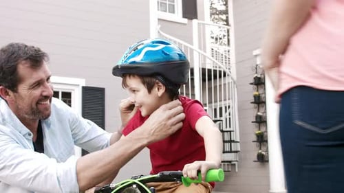 Parents Helping Child with Bicycle and Helmet Outdoors