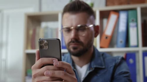 Hipster Young Man Browsing Smartphone Social Network in the Office In Focus Male Hands with Recent