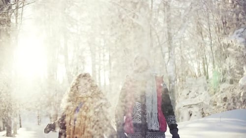 Jeune couple s'amuse à lancer de la neige dans un paysage forestier d'hiver