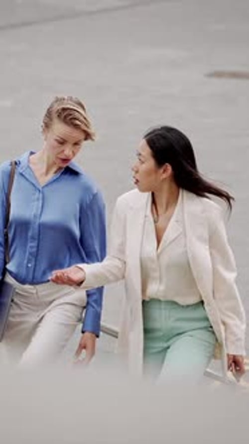 Two Women in Business Attire Walking and Talking