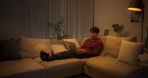 Man Relaxes Using Laptop on Couch At Home