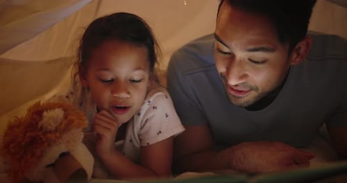 Father and Daughter Reading Book in Cozy Blanket Fort