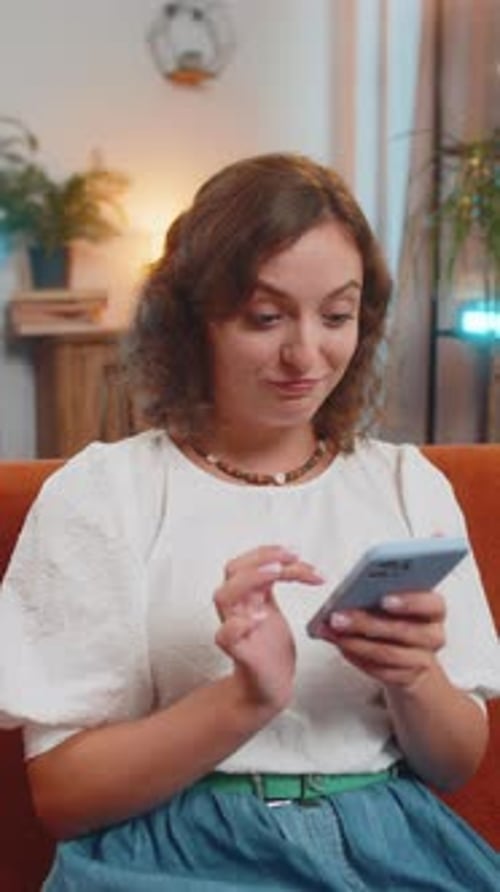 Woman Typing on Phone on Orange Couch