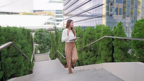 Asian young businesswoman using digital tablet while walking in the city.
