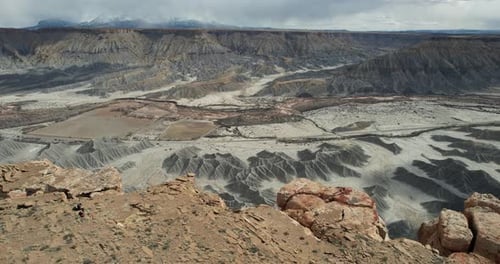 Aerial View of Woman Walking to the Edge of Cliff Above Abyss and Dry Desert Canyon, Utah USA