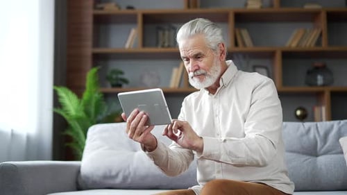 Senior Man Using Tablet on Couch Indoors