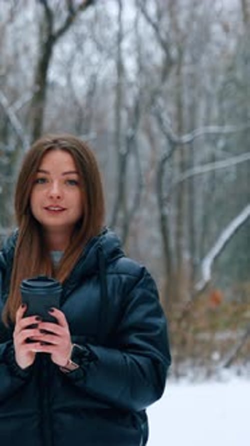 Woman with Coffee Standing in Snowy Winter Forest