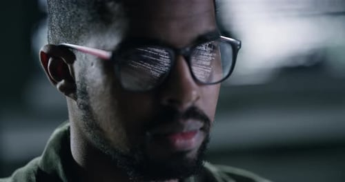 Visage, lunettes et code avec un programmeur noir travaillant dans un bureau sombre pour le traitement de données