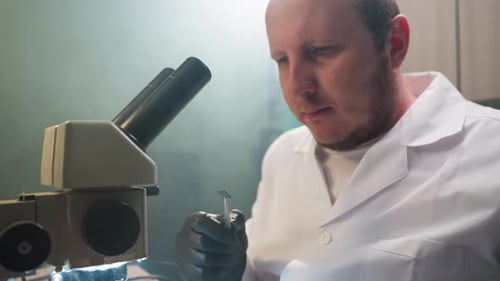 Scientist Examining Sample Under Microscope in Laboratory