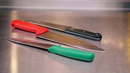Closeup of Large Slicing Knives Lying on a Metal Table in Professional Kitchen