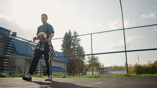 Man Dropping Volleyball in Court As Ball Bounces in Outdoor Sports Arena