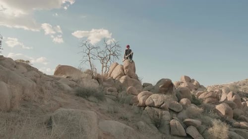 Young Punk musician plays electric guitar amidst desert barren landscape