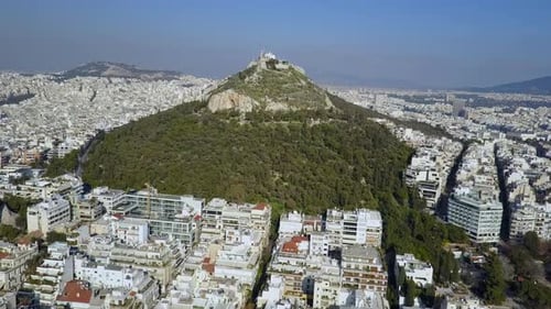 Wide orbiting sunny aerial of Mount Lycabettus Athens Greece, 4K.