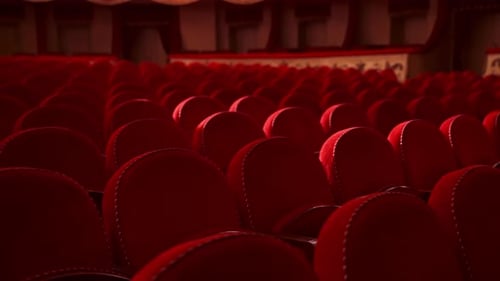 Red chairs background. Rows of comfortable chairs without people in a theatrical hall