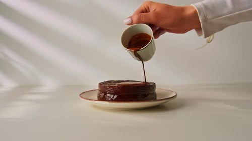 delicious freshly made chocolate sacher cake on a plate on a white background drizzled with hot
