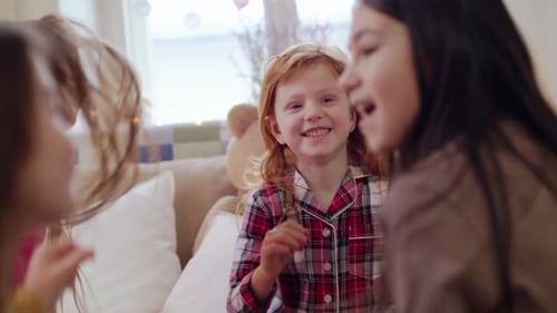 Smiling girls in pajamas sitting and chatting indoors