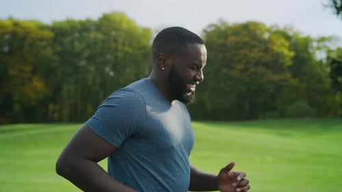 Portrait Of Tired Athlete Running In Park. Afro Man Training In Green Area In Slow Motion. Close ...