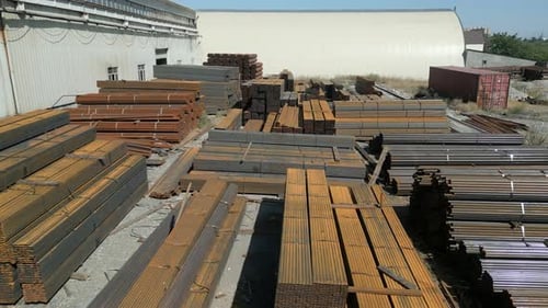 Aerial view of galvanized iron pipes stack and steel rectangular bars of metal