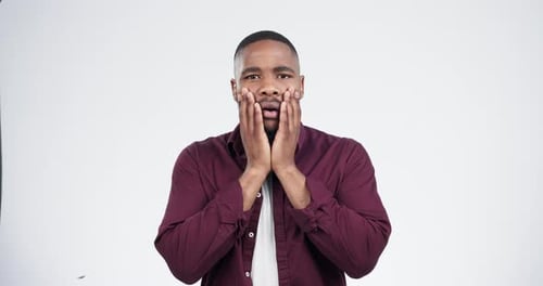 Face, surprise and fear of black man in studio isolated on white background with scary announcement
