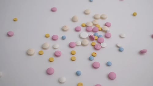 Colorful Pills Scattered on White Surface