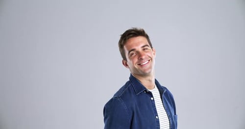 Face, happy and a confident young man in studio isolated on gray background to relax while feeling