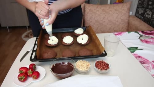Woman Adding Cream to Cookies on Baking Sheet