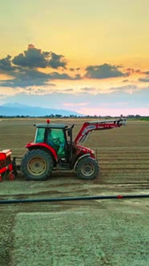 Verticle Tractor Working in a Field Surrounded by Farmlands - Aerial View