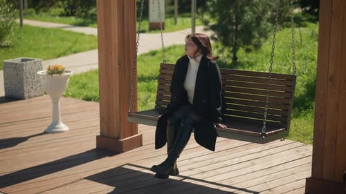Femme élégante sur une balançoire dans un parc verdoyant et ensoleillé