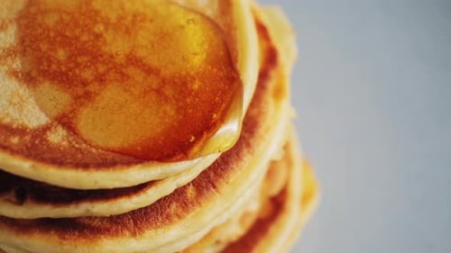 Close Up Pouring Honey Over Stack of Pancakes Concept of Sweet Brunch