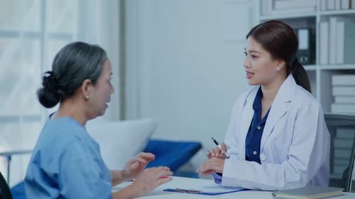 Female Doctor Consulting with Patient in Hospital Room