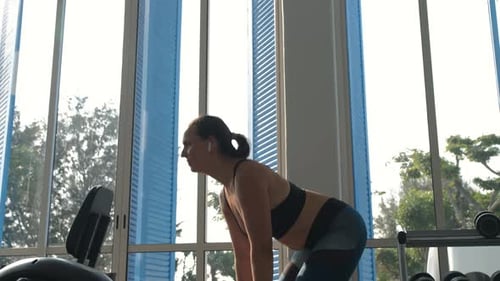 Young Woman Exercising with Dumbbells at Gym