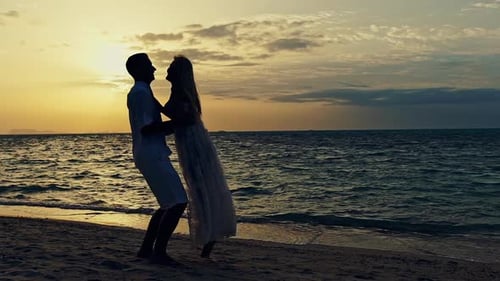 Young Couple Standing on a Beach at Sunset