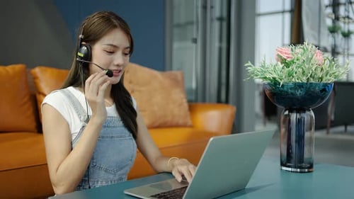 Consultant girl wearing headset with microphone sitting on sofa, freelance worker, call center