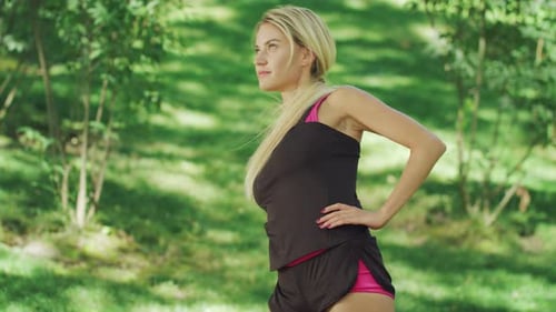 Athletic woman stretches in park on sunny day
