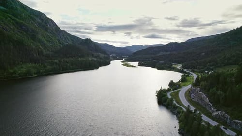 Winding River Flanked By Lush Green Mountains And Scenic Road