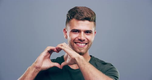 Smiling Young Adult Makes Heart Shape With Hands